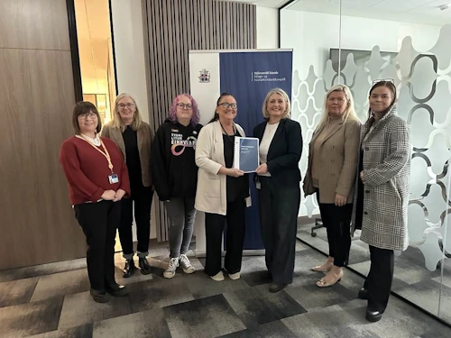 Inga Sæland, félags- og húsnæðismálaráðherra, tekur við skýrslunni frá Ástu Kristínu Benediktsdóttur, formanni starfshópsins. Með þeim á myndinni eru Helga Sif Friðjónsdóttir, Guðrún Skúladóttir, Margrét Oddný Leópoldsdóttir, Rakel Þorsteinsdóttir og Guðrún Rakel Eiríksdóttir.