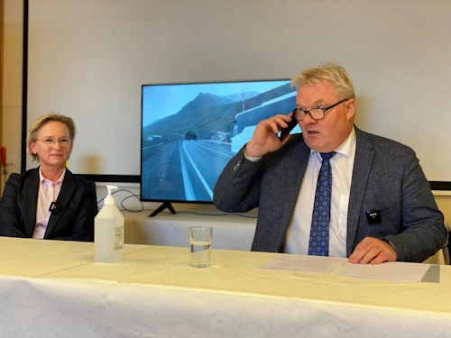 Sigurður Ingi Jóhannsson, samgöngu- og sveitarstjórnarráðherra, opnar Dýrafjarðargöng með símtali í vaktstöð Vegagerðarinnar á Vestfjörðum. Bergþóra Þorkelsdóttir, forstjóri Vegagerðarinnar fylgist með. Á skjánum sést rúta með grunnskólabörnum á Þingeyri bíða eftir að fara fyrst í gegnum göngin.